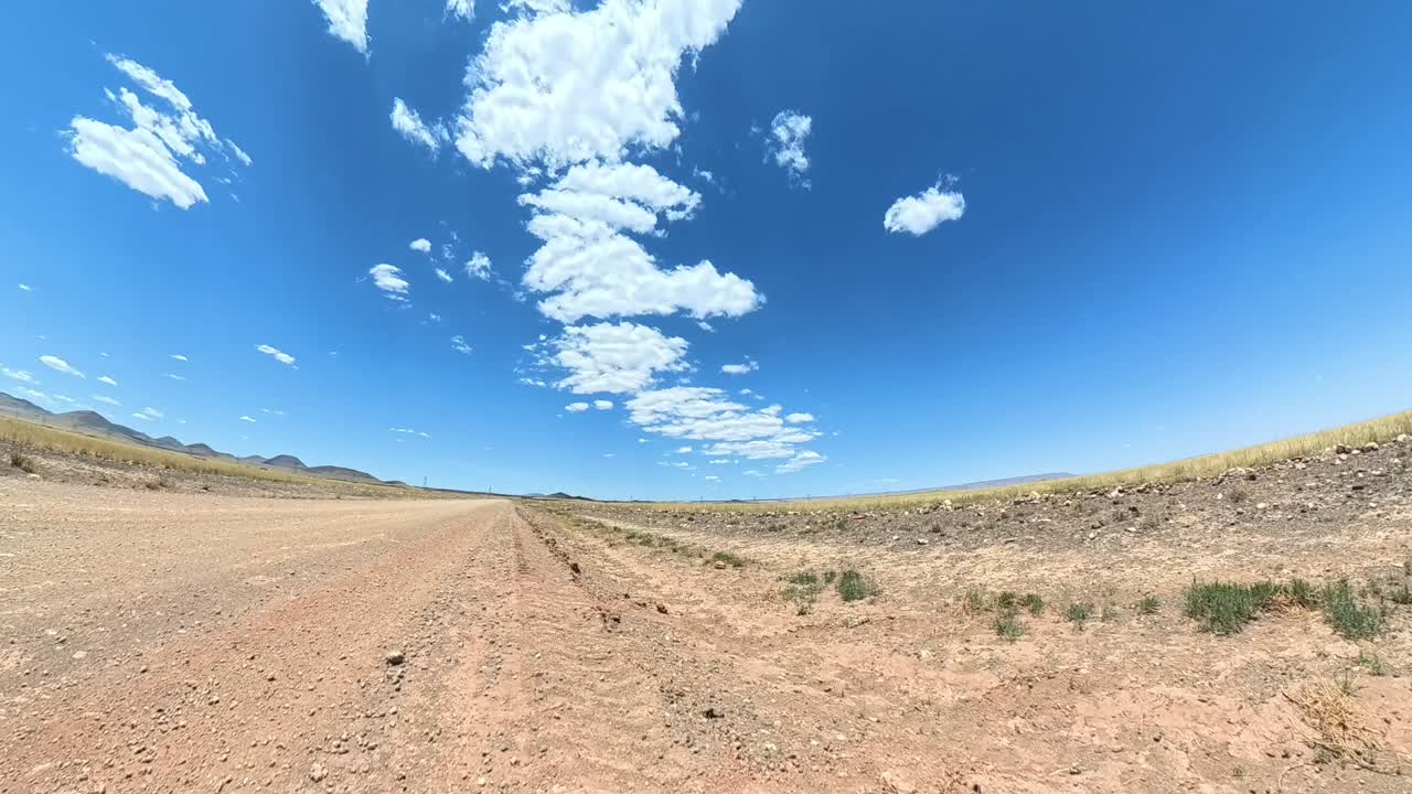 Static time lapse of clouds condensation over a dirt road as car drives by in a cloud of dust