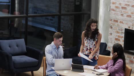 diverse male and female colleagues in discussion using tablet in casual office meeting, slow motion