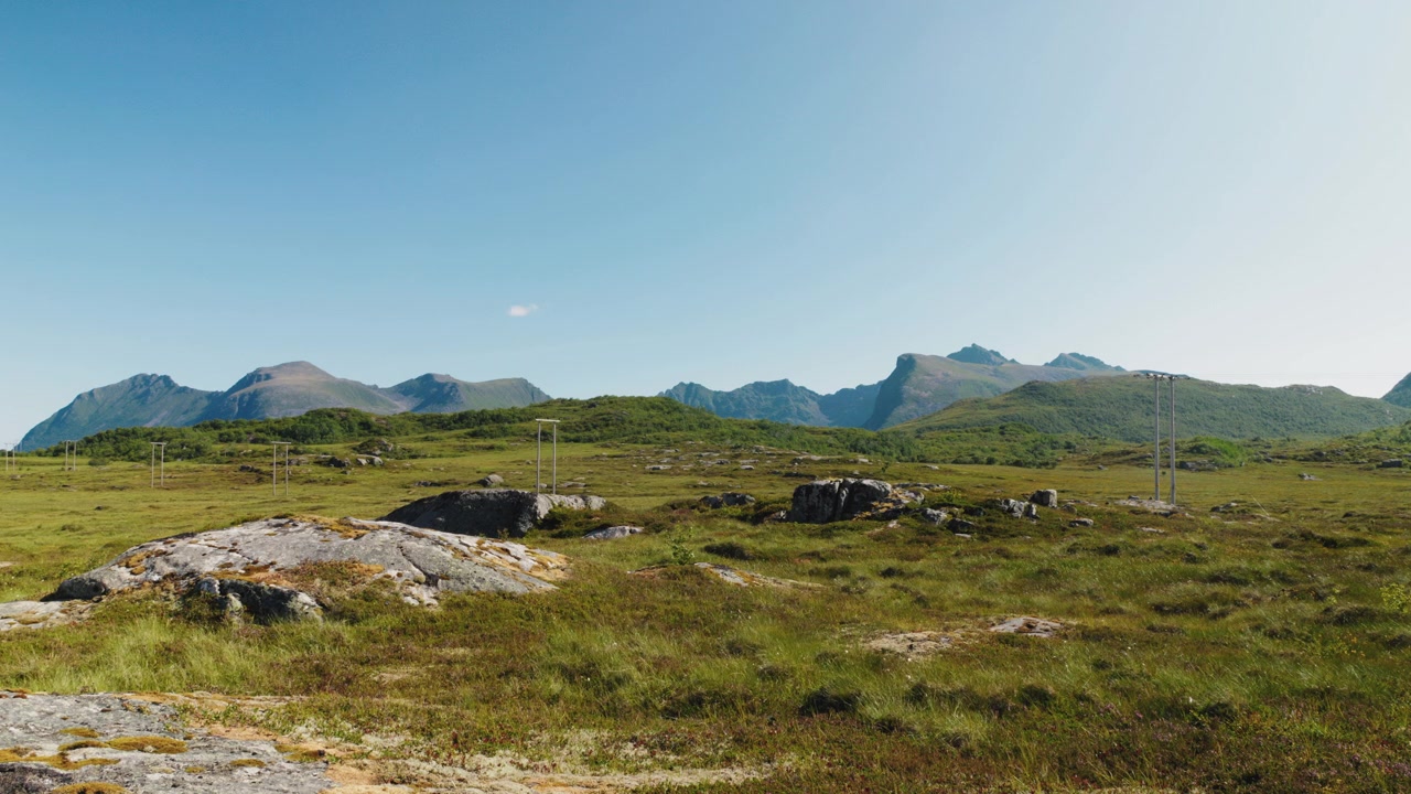 Paesaggio nordico estivo alle Lofoten, Norvegia, con catena montuosa, cielo azzurro e soleggiato.
