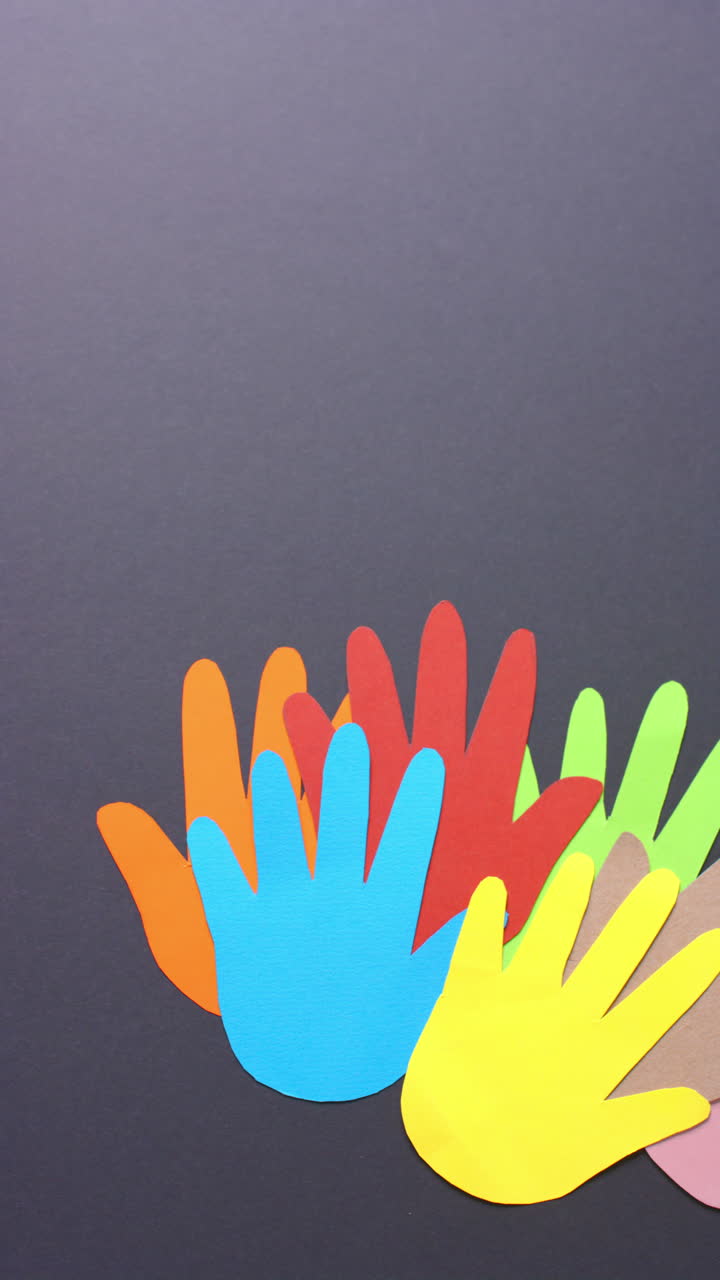 Vertical video of hands together made of colourful paper on gray background with copy space