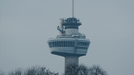 looking up at the euromast tower in rotterdam with people walking around the observation deck