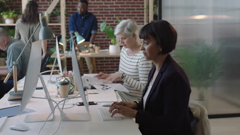 mature mixed race business woman using computer in diverse modern office workspace colleagues working on corporate project creative multi ethnic team