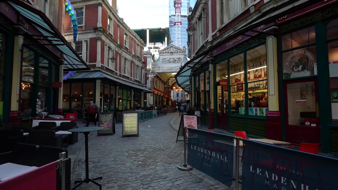 Leadenhall Market entrance with cafes and shops along a cobblestone street in London, UK