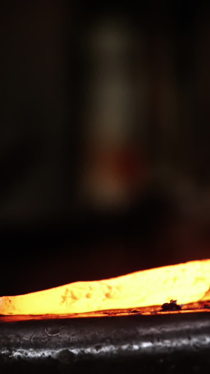 Primo piano di un fabbro che lavora una barra di ferro.