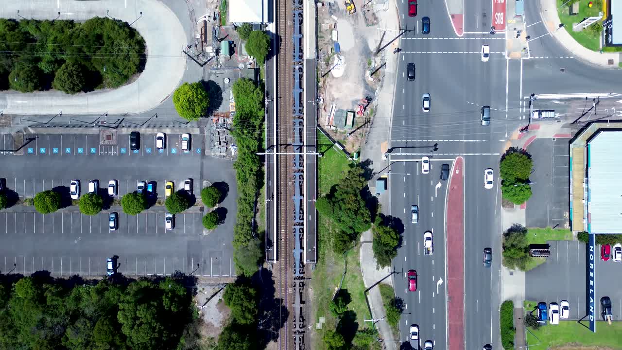 Drone aerial landscape of freight train cargo railway tracks Tuggerah station with car vehicle traffic on main road street intersection Central Coast Australia transport tourism