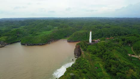 ocean waves crash on dangerous cliff rocks below tall lighthouse warning ships