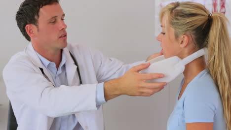 un médico colocando un soporte para el cuello a su paciente