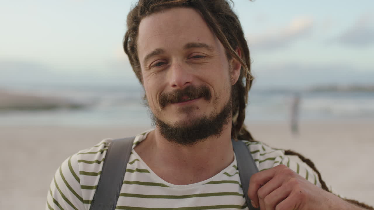 해변 에서 웃고 있는 드레드 로크 를 가진 매력적 인 무모 한 남자 의 초상화