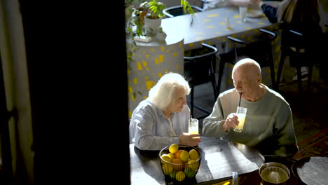 top view of a senior couple drinking limonade and kissing while they are sitting in a bar at sunset