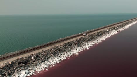 truck crossing the road over the pink and blue water lake in the great salt lake