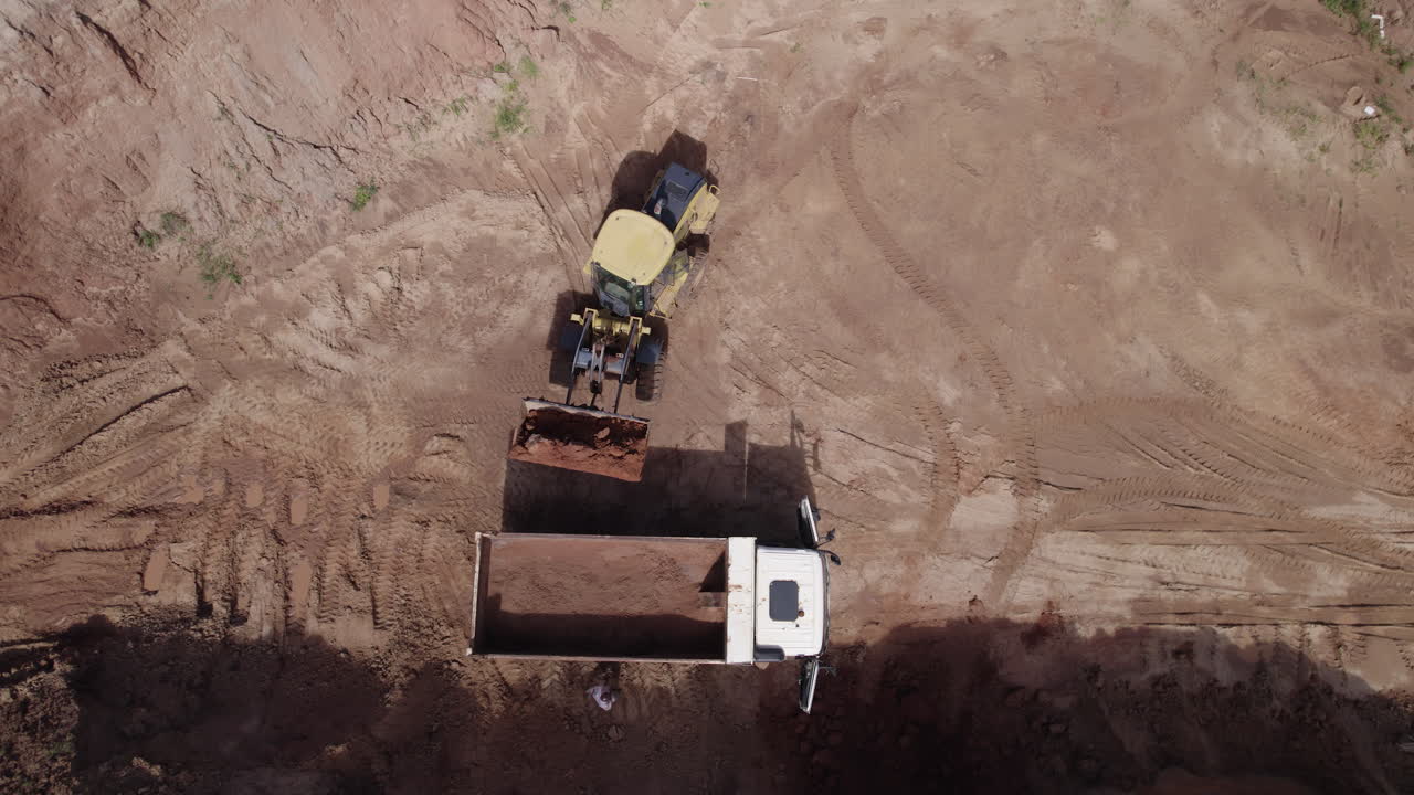 A drone shot of a digger loading into a truck on a property development.
