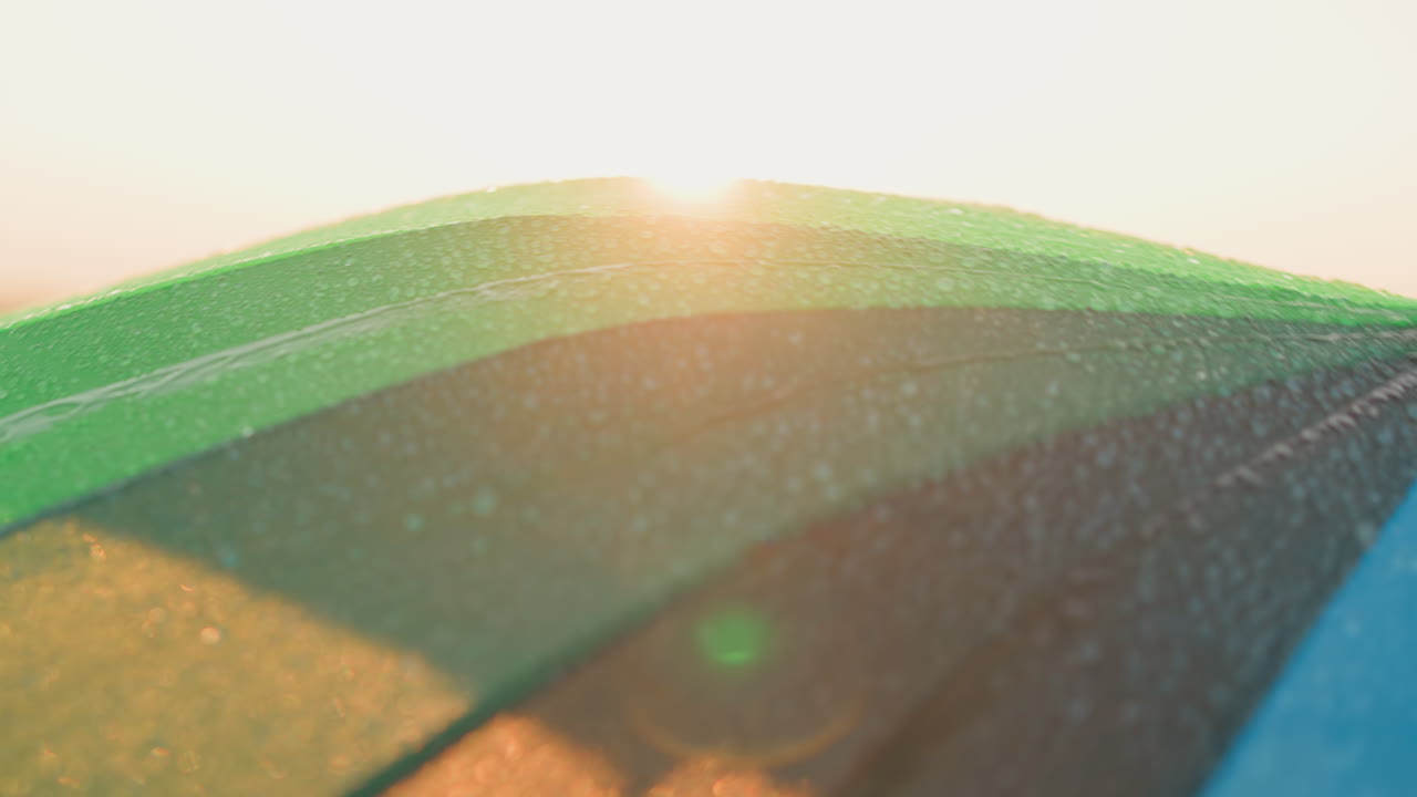 회색 하늘 에 대비 한 우산 의 색채 들 이 눈에 띄고 있다. 산책자 가 항해 할 때, 다채로운 우산 이 머리 위 를 회전 한다