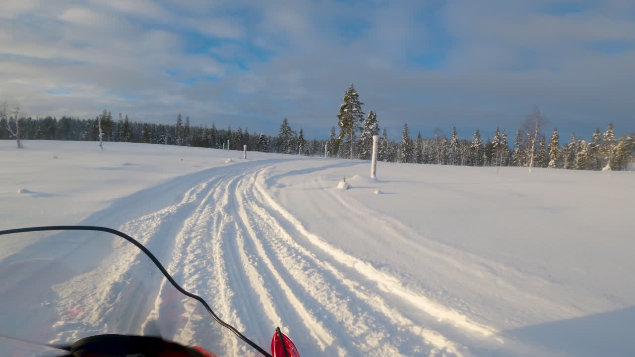 Lapland, İsveç'te karlı orman yoluna giren bir kişinin bakış açısından kar aracı sürmesi.