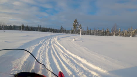 POV-person-driving-snowmobile-into-snowy-woodland-trail,-Lapland,-Sweden