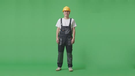 full body of asian man worker wearing goggles and safety helmet standing and smiling to camera in the green screen background studio