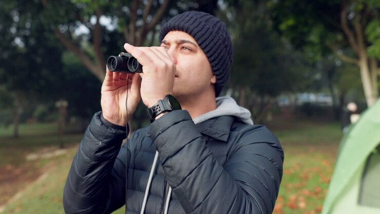 Binocolo, natura e giovane uomo in campeggio