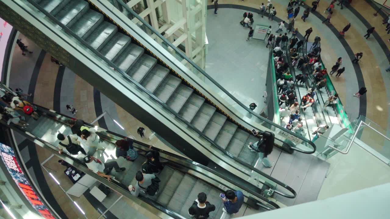 Busy shopping mall escalators filled with people moving up and down in slow motion