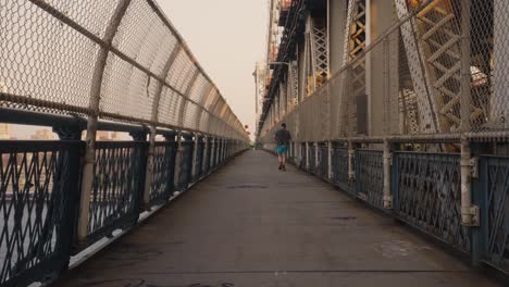 slow motion following shot showing male jogger jogging on manhattan bridge in new york city