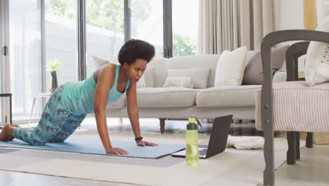 happy african american wearing sportswear, exercising, using laptop