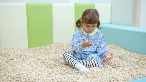 Café-Infantil:-Niña-De-3-Años-De-Raza-Mixta-Jugando-Con-Bloques-De-Madera-En-La-Piscina-De-Arena-En-La-Sala-De-Juegos-Interior