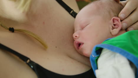 a newborn baby snuggles close to mother, handheld close up