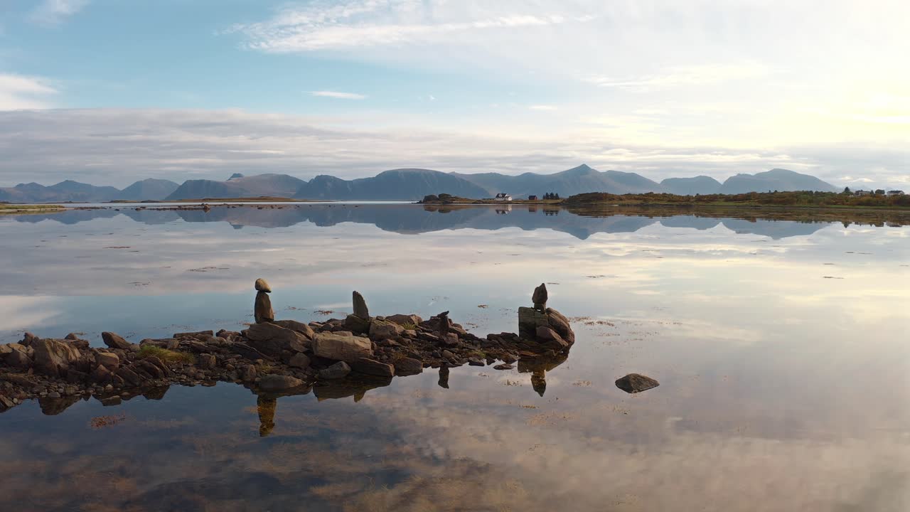 Tranquil coastal landscape with stone formations reflected in the still water in Vestarelen