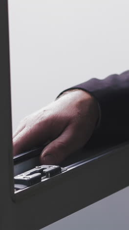 cu, slow motion: confident businessman in dark suit walks to open window and leans out having break in modern company office extreme close view