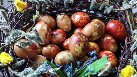 a nest of intricately dyed easter eggs decorated with spring flowers in cēsis, latvia - close up