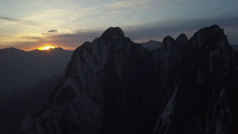 Antena-De-Montaña:-El-Sol-Dorado-Se-Pone-Detrás-De-Picos-Distantes,-Cumbres-De-Granito