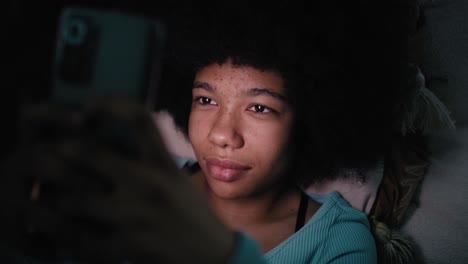 adolescente navegando por el teléfono móvil en la sala de estar por la noche