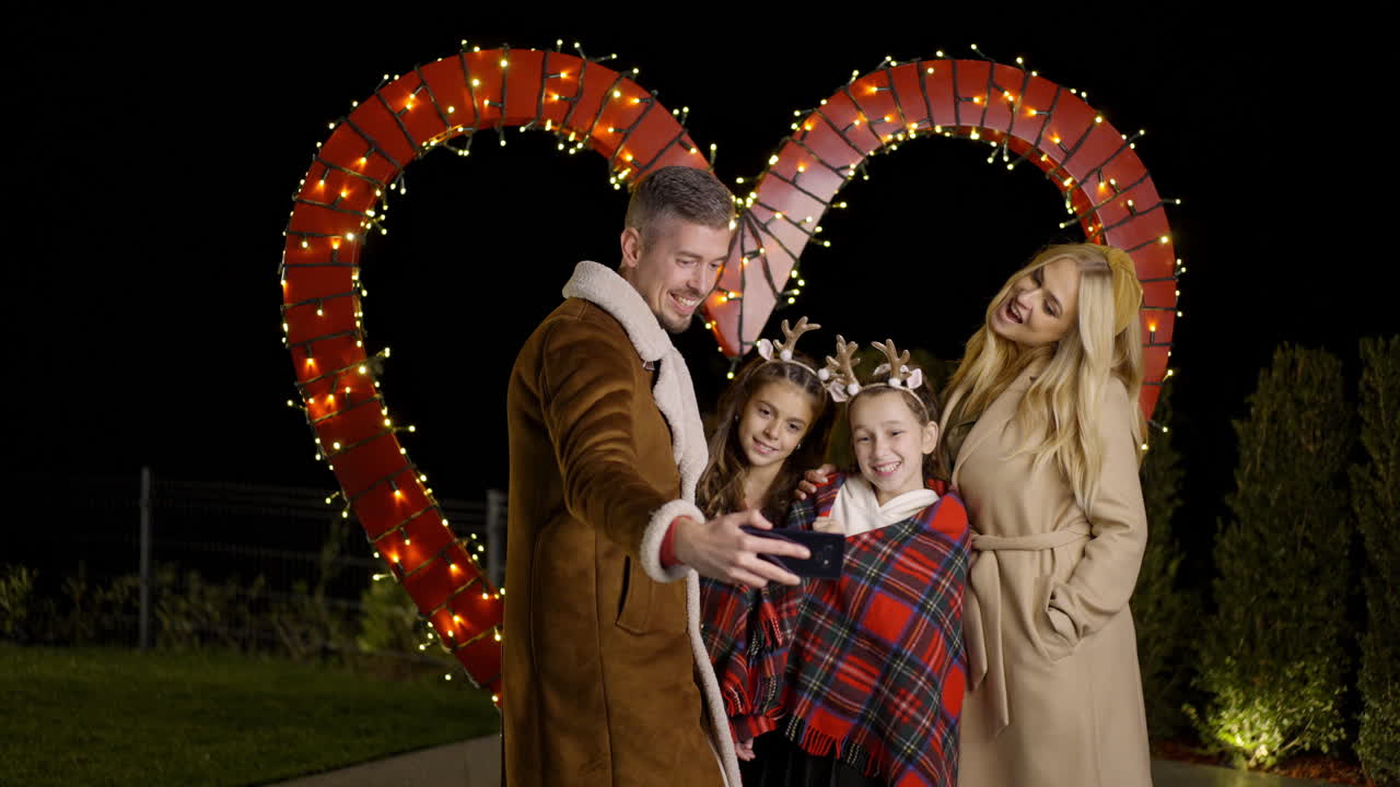 Family taking a selfie in front of a heart shaped light installation