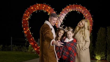 family taking a selfie in front of a heart shaped light installation