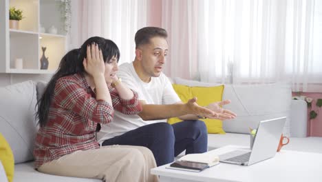 the couple is upset by what they see on the laptop.