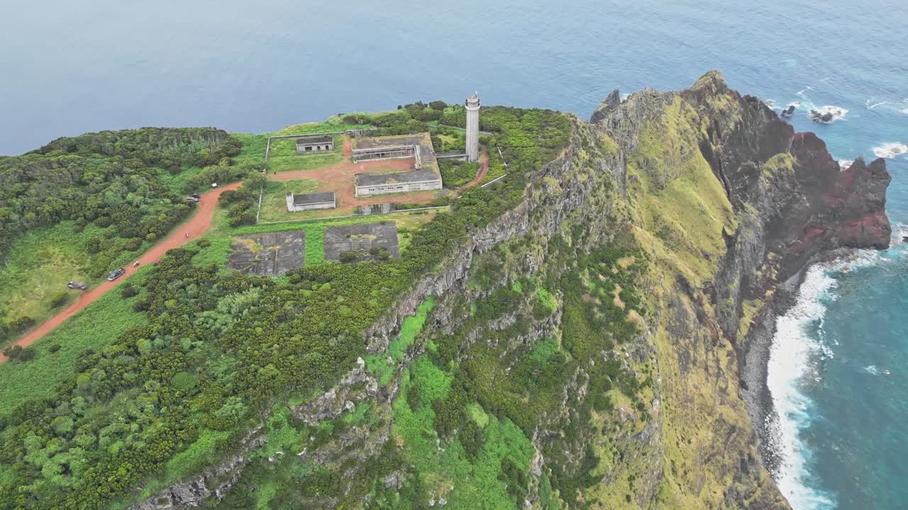 Ngọn hải đăng Farol da Ponta dos Rosais trên đảo São Jorge, Azores, Bồ Đào Nha, hiển thị tháp hải đăng và các tòa nhà phụ trợ bị bỏ hoang trên vách đá biển cao của Đại Tây Dương, góc nhìn từ trên cao.