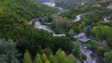 a cinematic aerial showcase of nestorio village by the forested riverside, greece