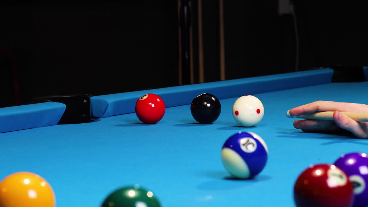 Playing a game of pool billiards hitting balls and white ball going into a pocket