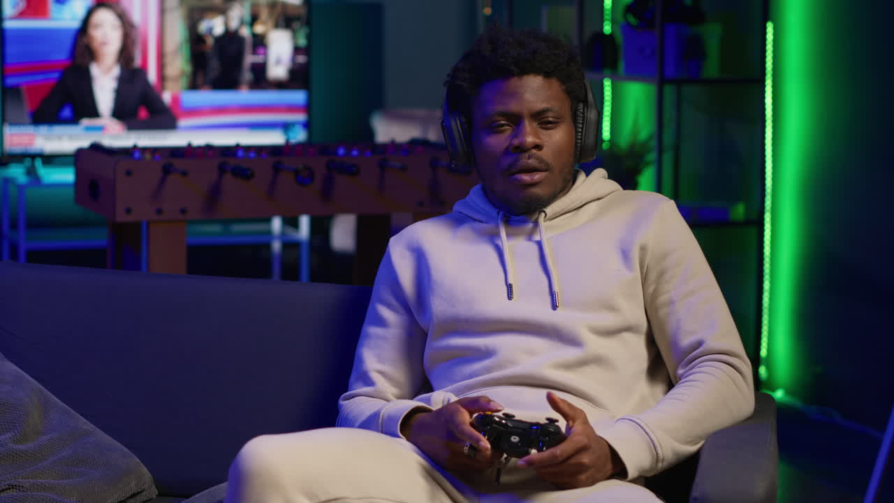 African american player relaxing at home sitting down on couch, excited to play games and enjoy leisure time. Person on sofa in a decorated living room, playing video games on console. Camera A.