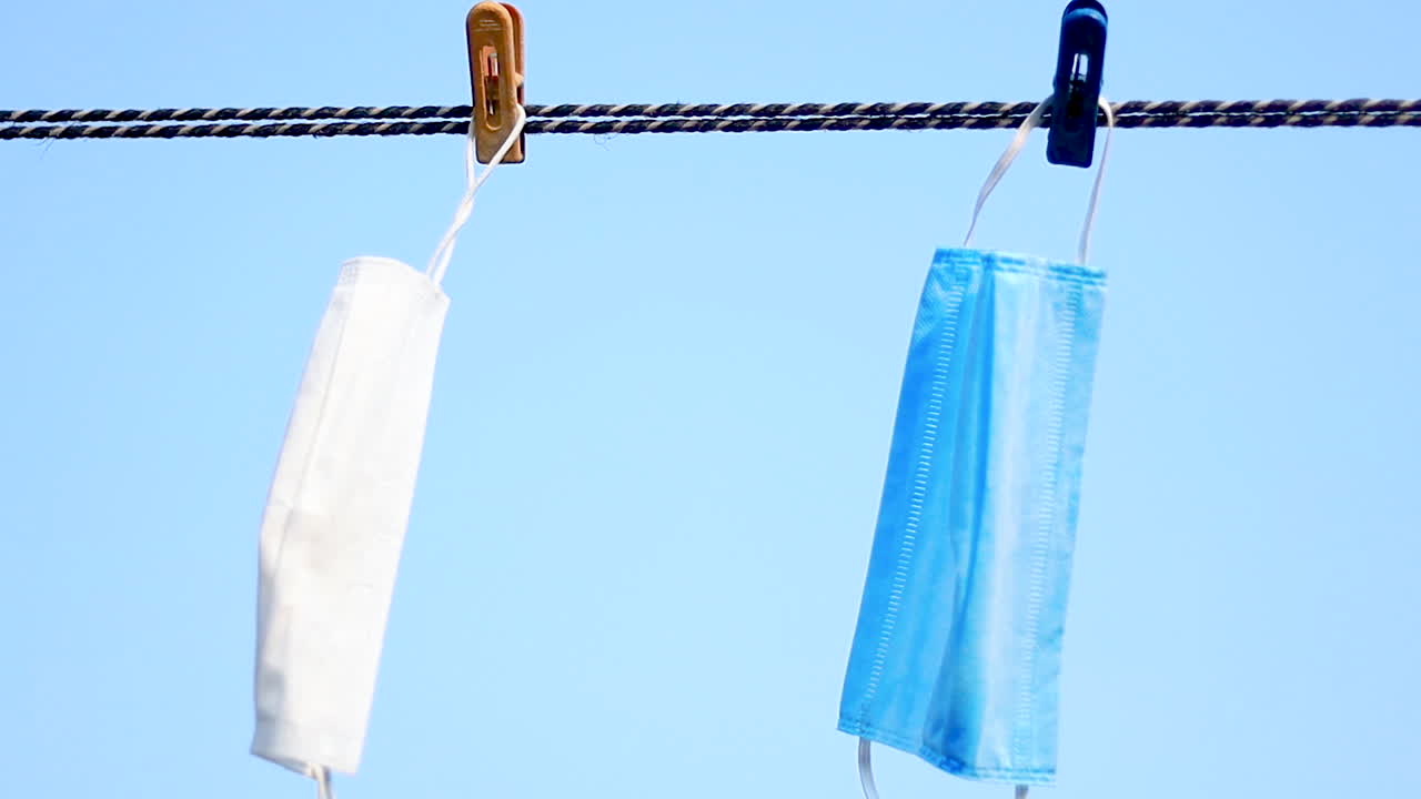 Surgical face mask for coronavirus hanging on clothesline string with clothespin. Reusing masks can minimize waste, protect the environment, and help to solve the current shortage of supplies