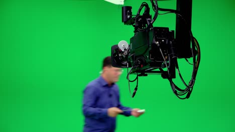 camera crane jimmy jib follows the announcer in a professional chroma key studio. the professional looks all the shooting equipment; lights, camera, green screen