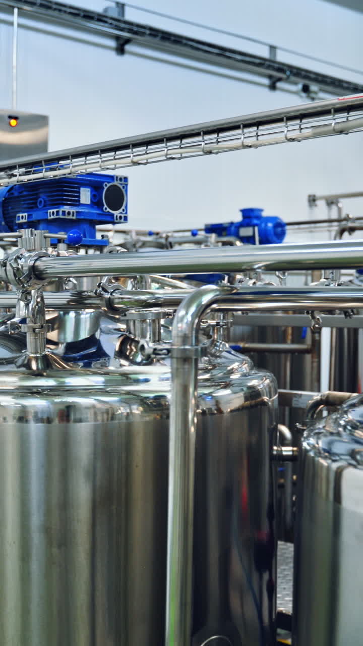 Contemporary milk making factory indoors. Huge bowls for mixing milk and water. Special equipment for preparing cheese. Vertical video