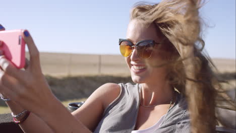 hermosa mujer feliz tomando una selfie en un viaje por carretera en un coche convertible