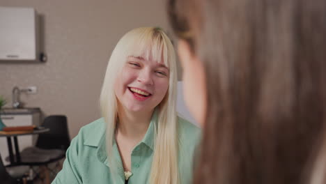 close up of cheerful blonde girl with open mouth laughing as she successfully catches last popcorn thrown by friend during fun indoor moment