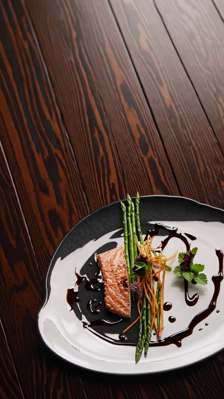 Elegant top-down video shot of gourmet salmon dish with asparagus and garnish on a stylish plate