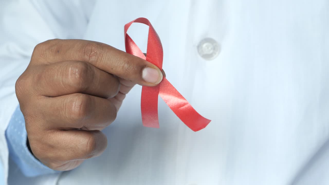 médico sosteniendo una cinta roja para la conciencia