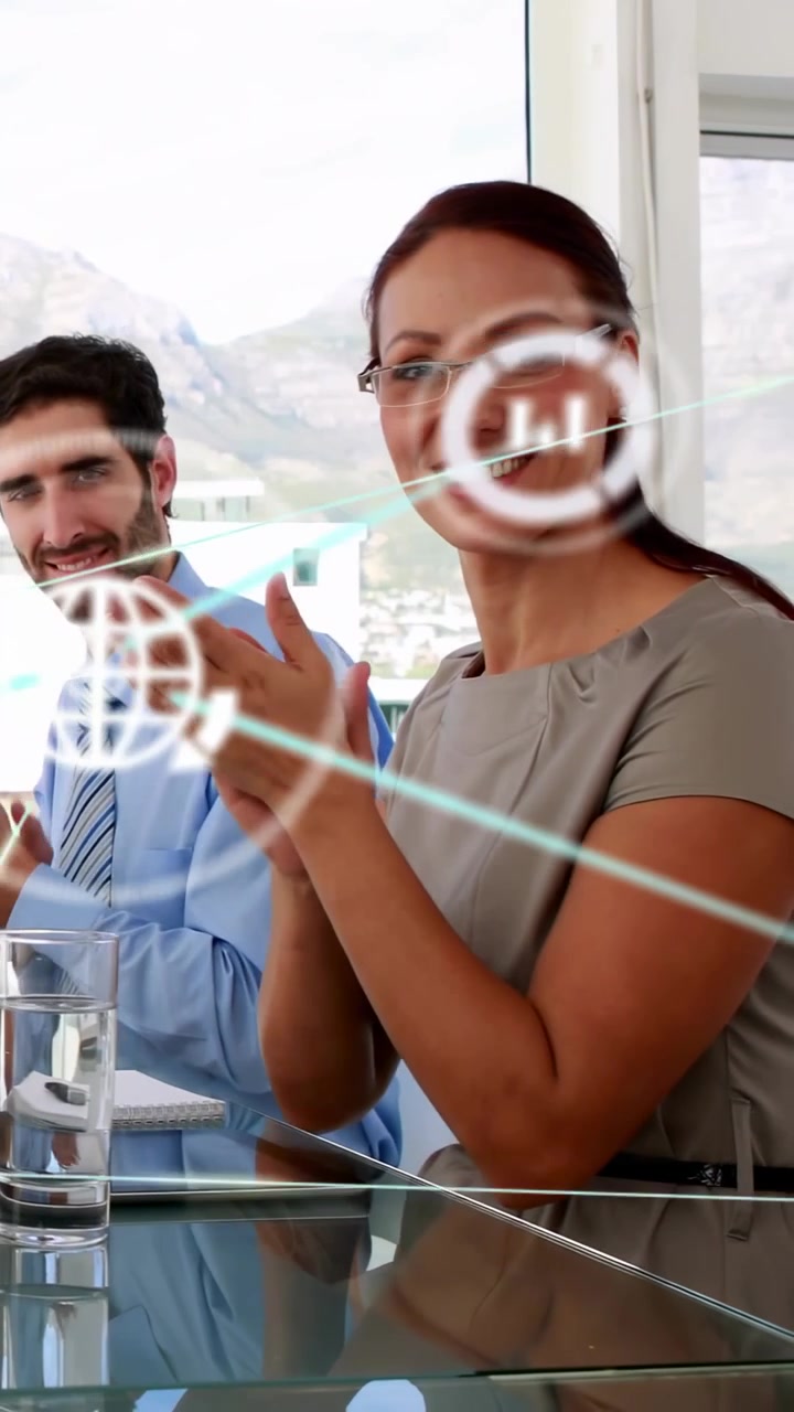 Video verticale: Due donne che applaudono a un tavolo di vetro dopo una presentazione in ufficio, con un overlay 3D che si eleva sopra il team
