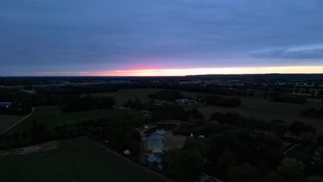 Vista-Aérea-Nocturna-Del-Parque-Glamping-En-El-Norte-De-Limburg-Durante-La-Puesta-De-Sol-En-El-Horizonte