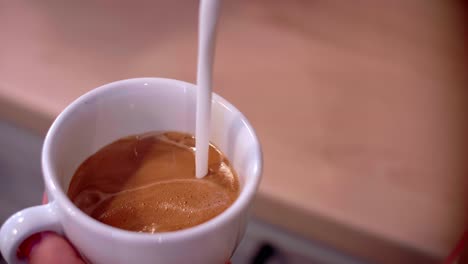 parte del barista vertiendo leche en el café en la cafetería