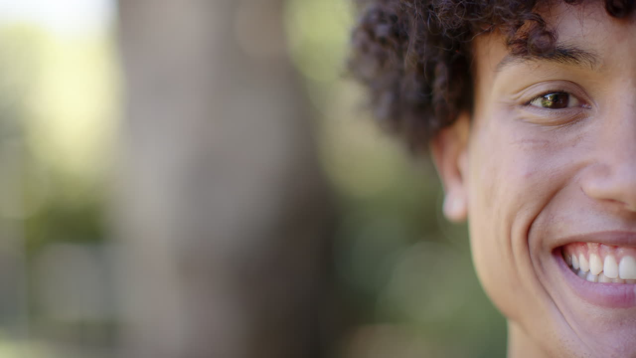 Smiling young man outdoors, showing happiness and joy in natural setting, copy space