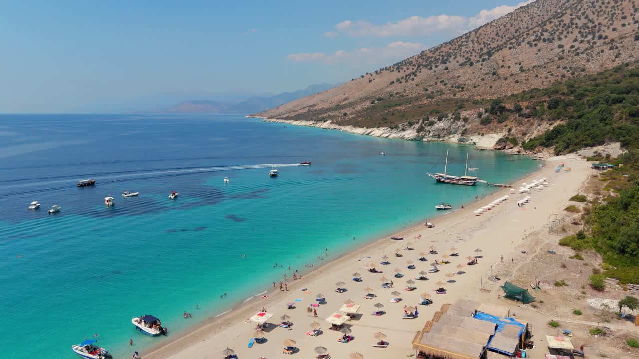 Turquoise water and sun-kissed beach with boats and sunbeds, Albania coastal view