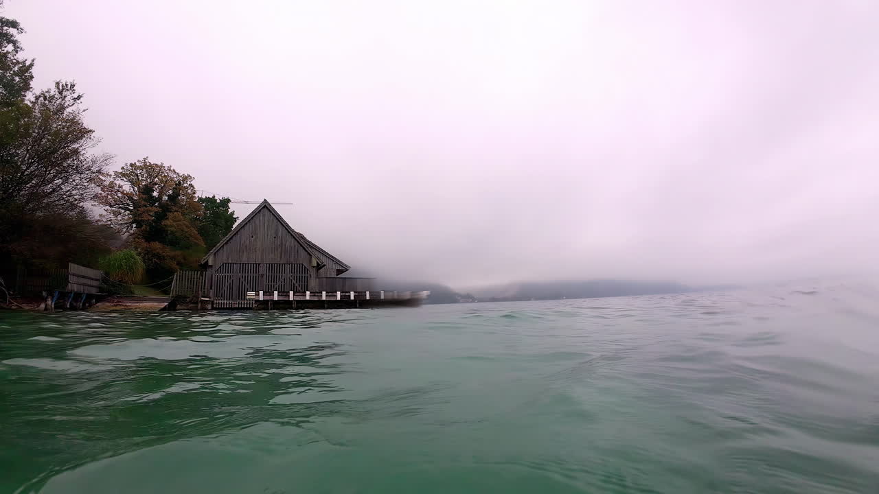 먼지 에 안개 가 인 산 들 이 있는 호수변 에 있는 나무 의 오두막